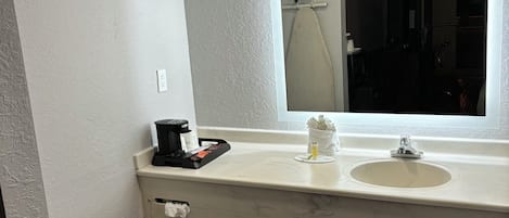 A bathroom with a white marble sink, a mirror, and a window.