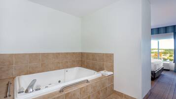 Un bagno moderno con una vasca da bagno ampia, un sostegno e vista sulla città attraverso una finestra.