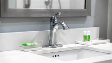 A modern bathroom with a chrome faucet, a mirror, and a soap dispenser on the counter.