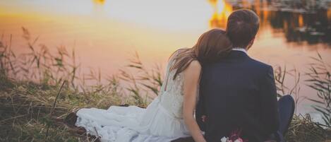 A couple sitting by a body of water during sunset.