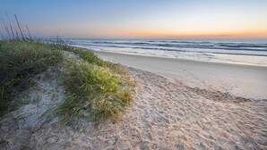 A beach with sand and grass, leading to the ocean. - Holiday Inn St. Augustine - World Golf by IHG (St. Augustine)