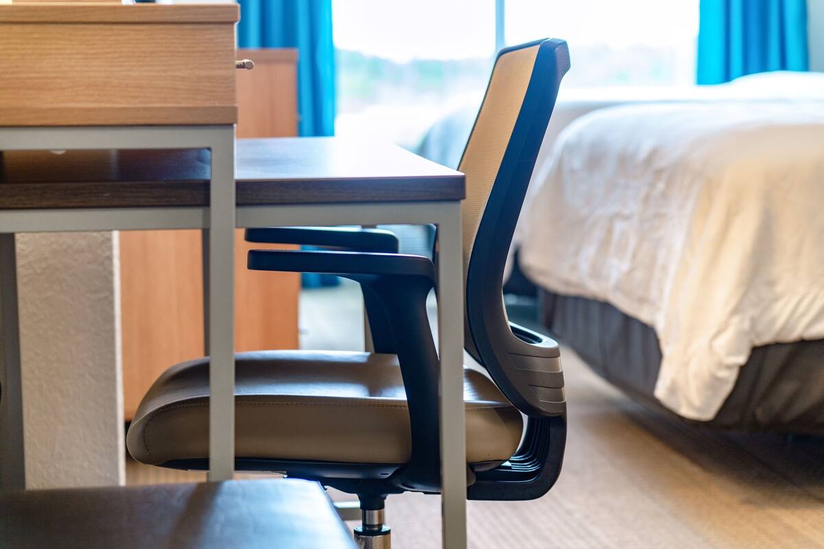 Une chambre d’hôtel avec un lit, un bureau et une chaise.
