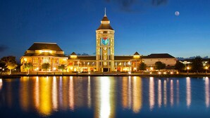 A waterfront hotel with a prominent clock tower, reflecting lights on the water. - Holiday Inn St. Augustine - World Golf by IHG (St. Augustine)