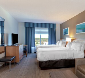 A hotel room with a large bed, a desk, a chair, a television, and a window with curtains.