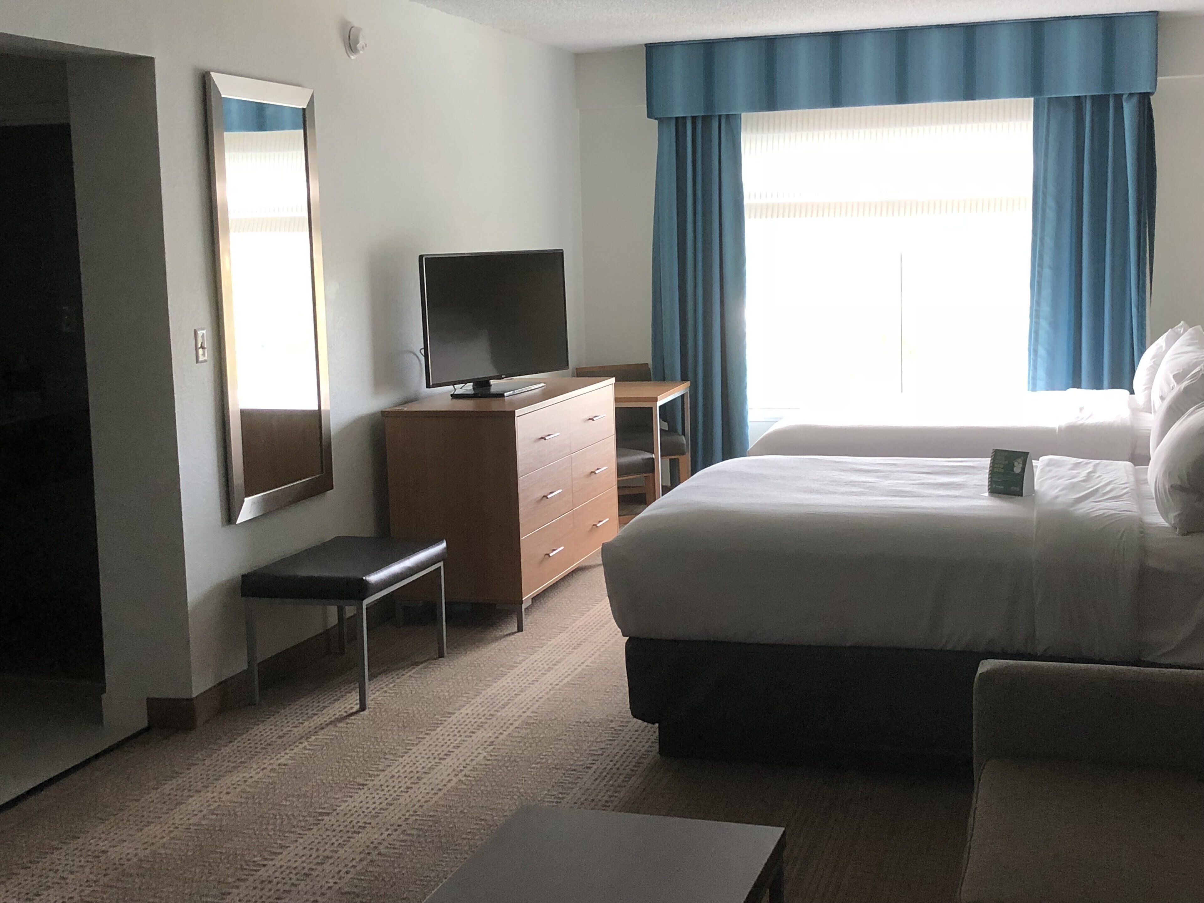 Une chambre d’hôtel comprenant un lit, un bureau, une télévision, une commode et un miroir.
