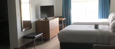 Une chambre d’hôtel comprenant un lit, un bureau, une télévision, une commode et un miroir.
