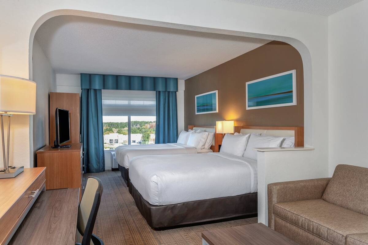 Une chambre d’hôtel avec deux lits, un bureau, une télévision et une vue sur la ville.