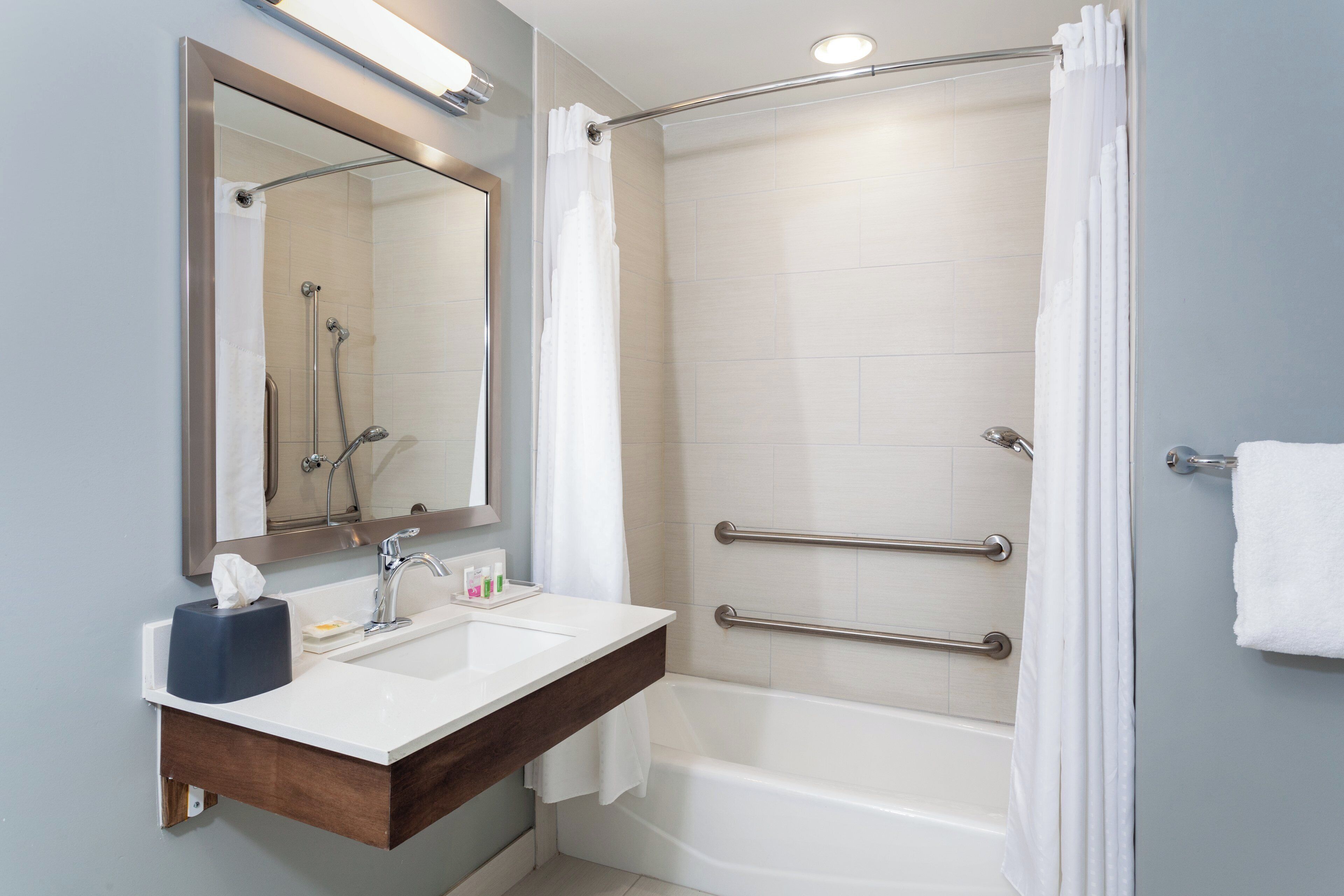 Une salle de bain moderne avec une douche, un lavabo avec un miroir et une baignoire.
