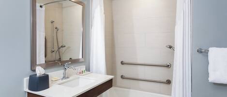 A modern bathroom with a shower, a sink with a mirror, and a bathtub.