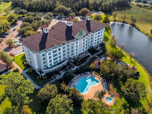 A large hotel with a swimming pool, tennis courts, and a lake view.
