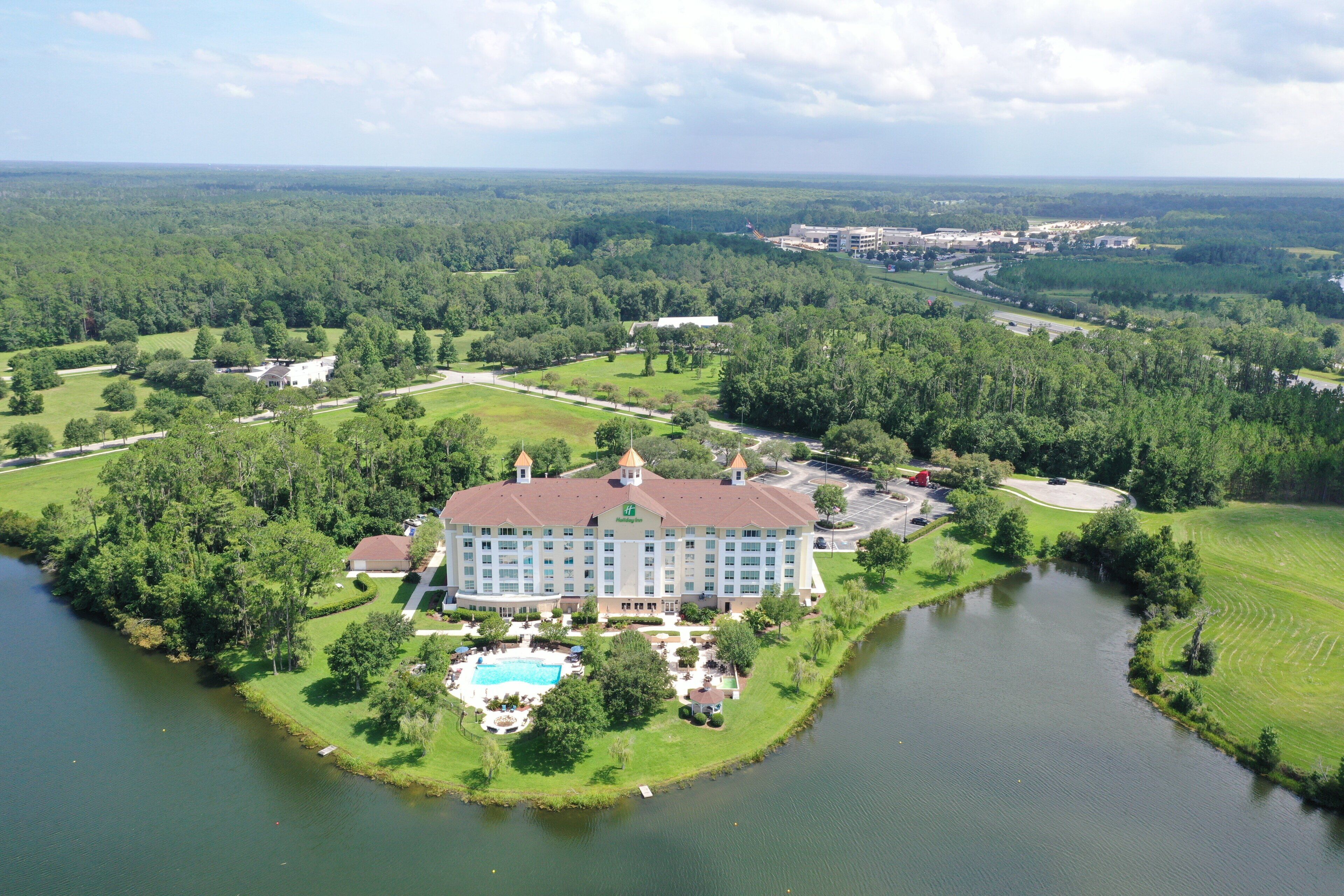 A large hotel with a central courtyard, a swimming pool, and a lake.