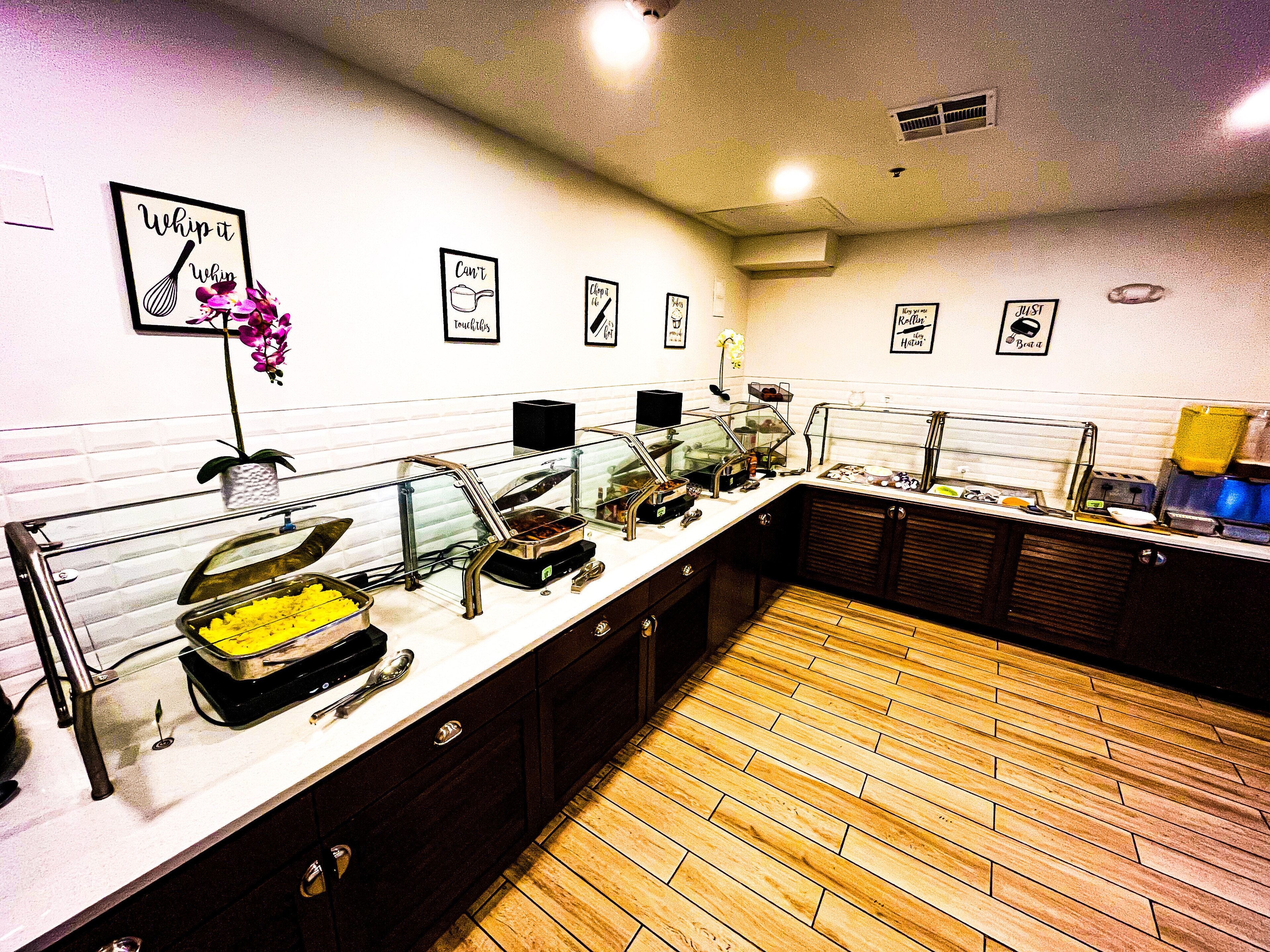 A kitchen with a white tiled backsplash, wooden floor, and various kitchen appliances.