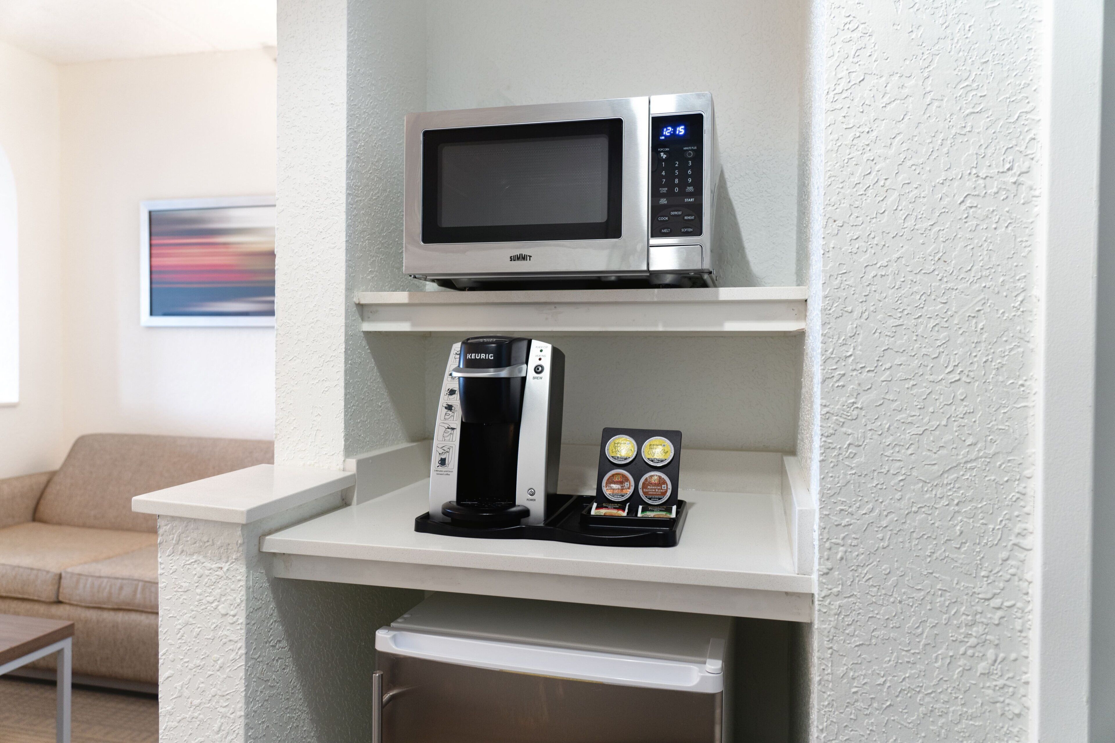 A kitchenette with a microwave on the upper shelf and a coffee maker on the lower shelf.