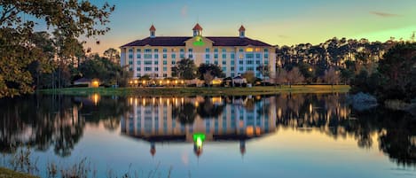 A large hotel with a symmetrical facade, a central tower, and a reflection in the water.
