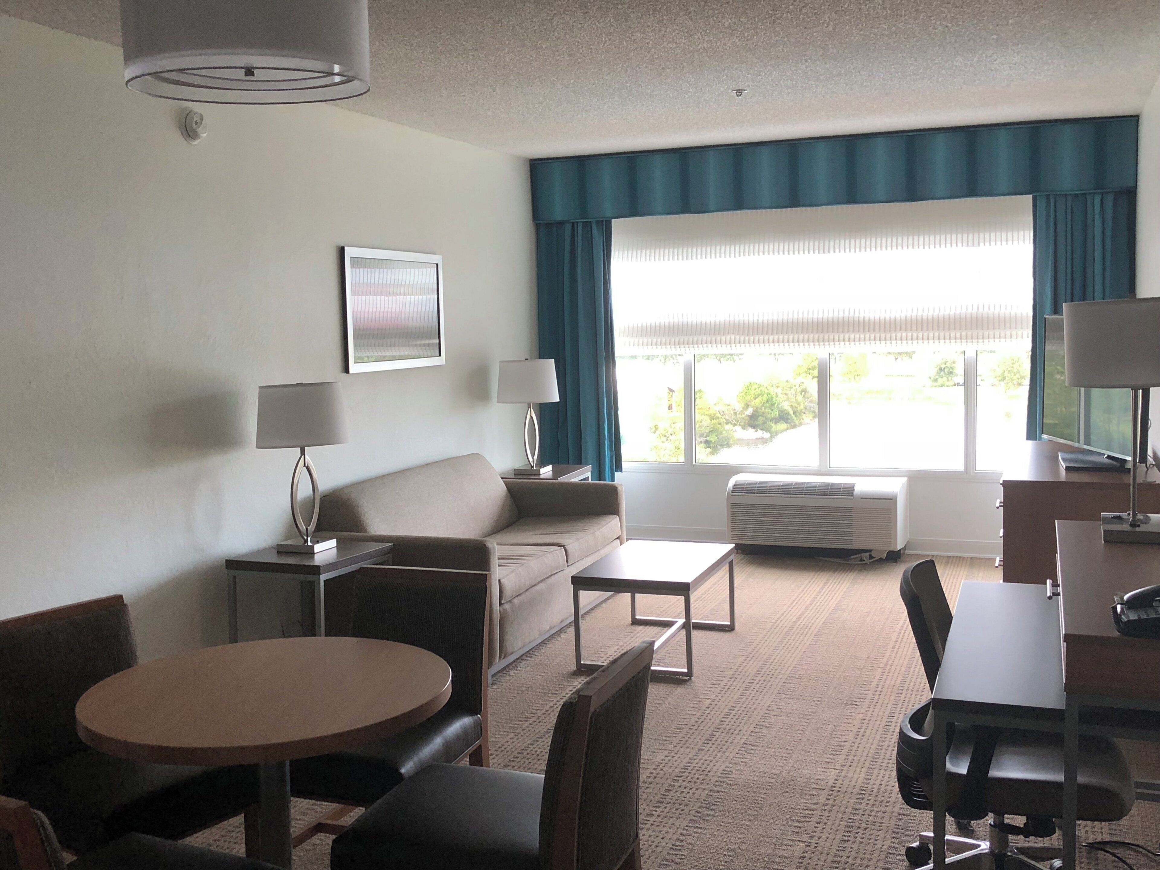 Une chambre d’hôtel avec un canapé, une table ronde, un bureau et un téléviseur.