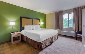 A hotel room with a bed, bedside lamps, a nightstand, a window with curtains, and a radiator. - Extended Stay America Select Suites Tampa Airport Memorial (Tampa)