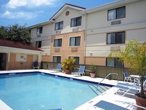 A swimming pool with lounge chairs, a fenced area, and a building with multiple windows and balconies. - Extended Stay America Select Suites Tampa Airport Memorial (Tampa)