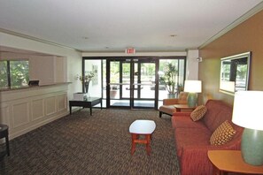 A lobby with a reception desk, a sofa, a small table, and a lamp. - Extended Stay America Select Suites Tampa Airport Memorial (Tampa)