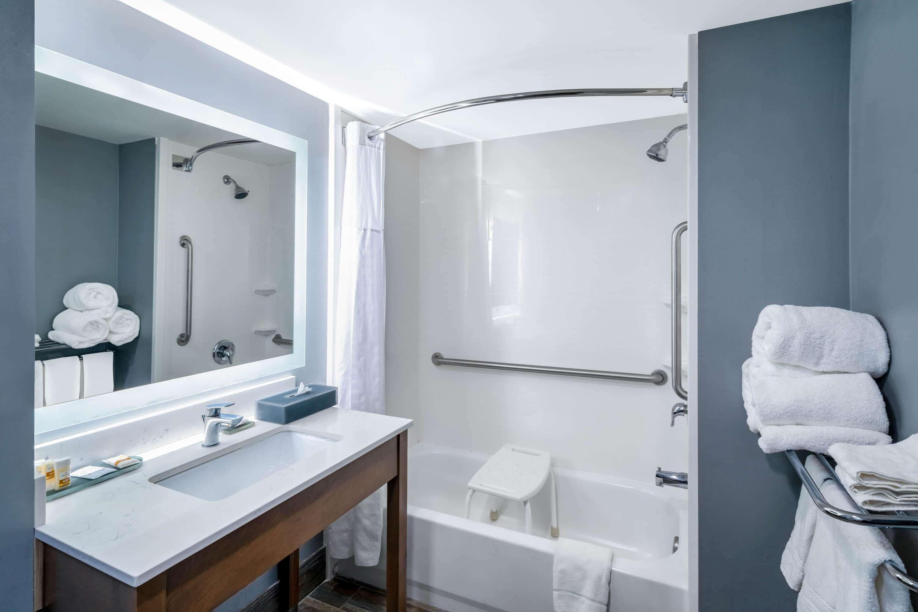 A modern bathroom with a shower, a bathtub, a vanity with a mirror, and a towel rack.