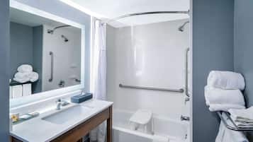 A modern bathroom with a shower, a bathtub, a vanity with a mirror, and a towel rack.