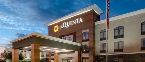 Un hôtel La Quinta doté d’une façade moderne, d’une entrée couverte et arborant le drapeau américain.