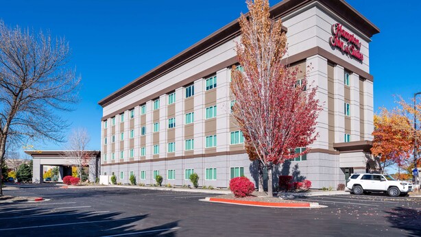 A Hampton Inn hotel with a modern facade, multiple floors, and a parking lot.