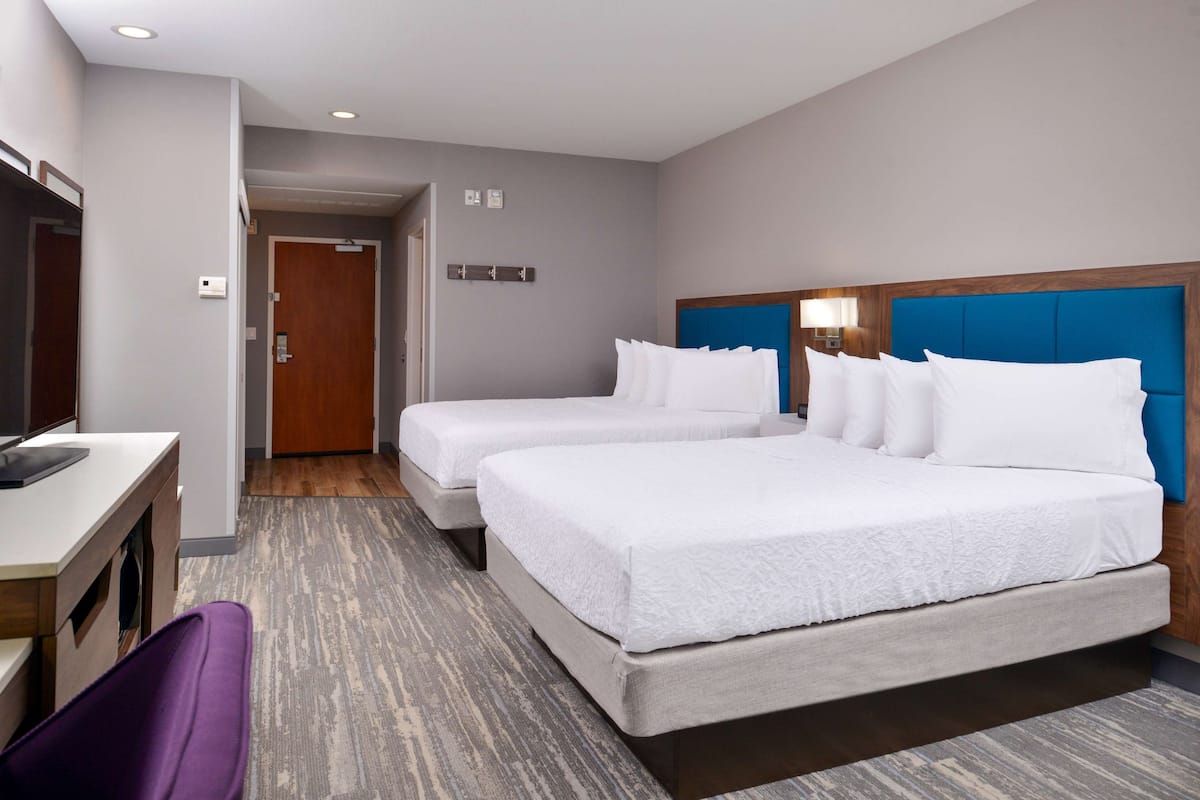 Una habitación de hotel con dos camas, un escritorio y una silla.