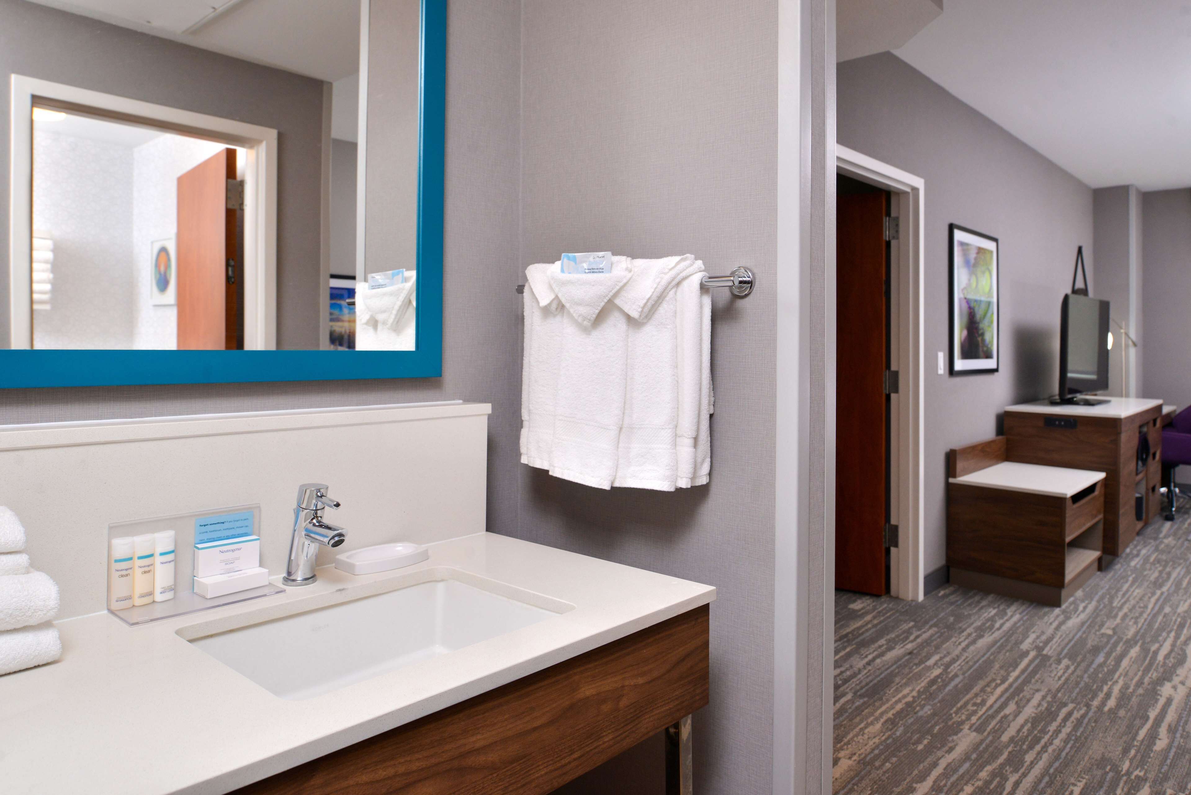 A hotel bathroom with a large mirror, a sink, and a towel rack.