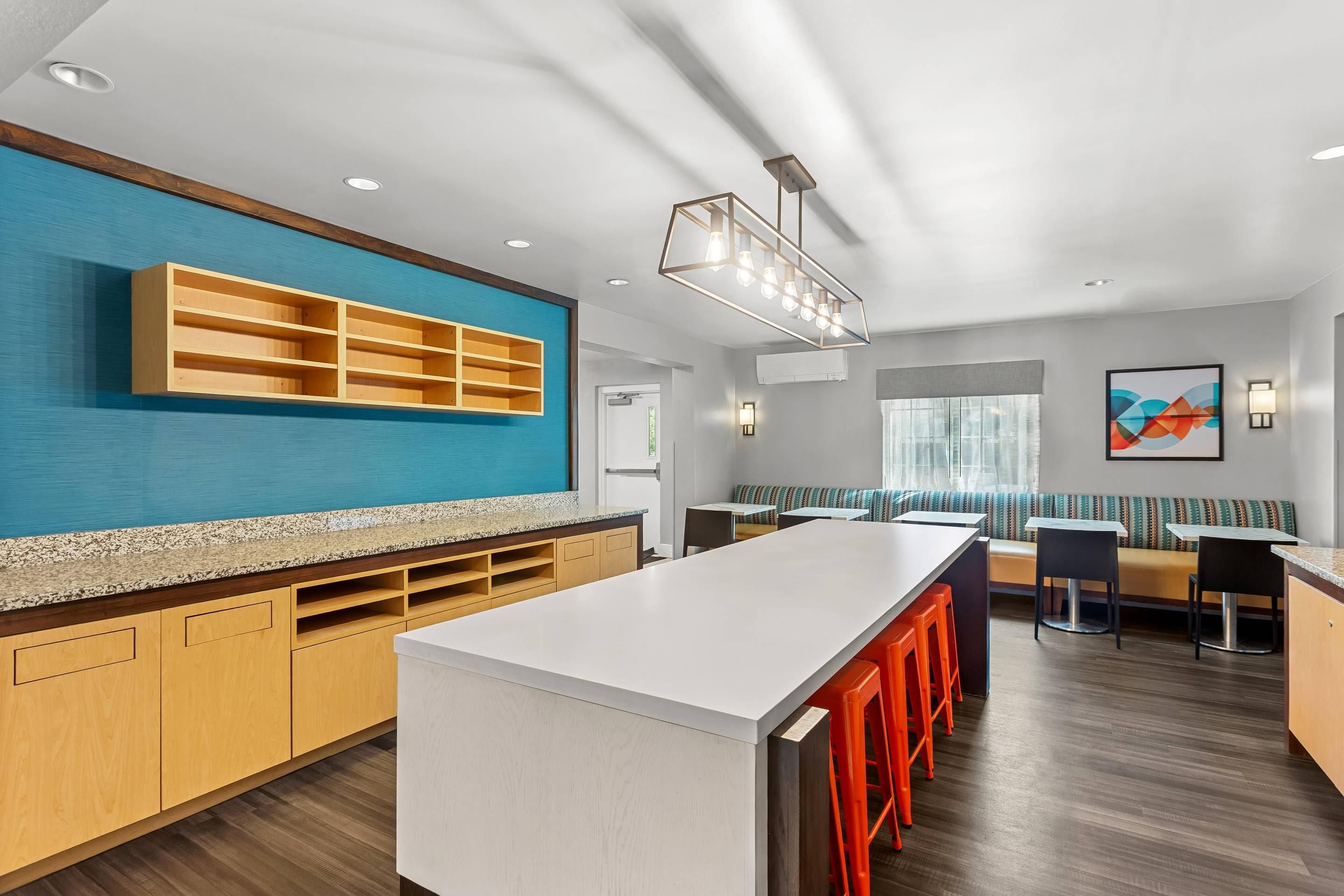 Una cocina moderna con una isla central, armarios de madera y una pared de acento azul.