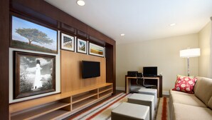 En moderne stue med et fladskærms TV, en sofa, et sofabord og et TV-møbel med billeder i rammer.