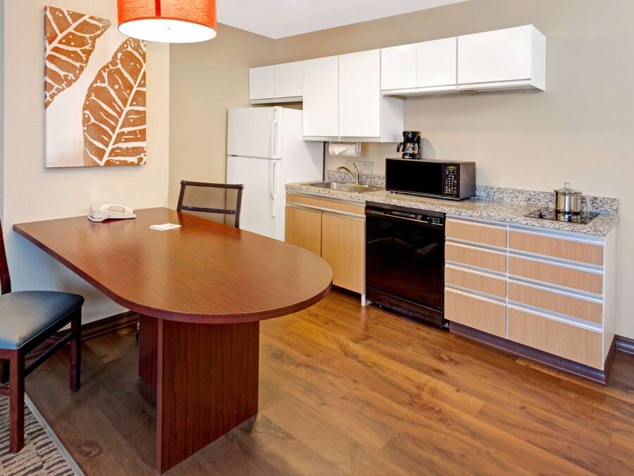 A compact kitchen with white cabinets, a microwave, a refrigerator, and a dishwasher.