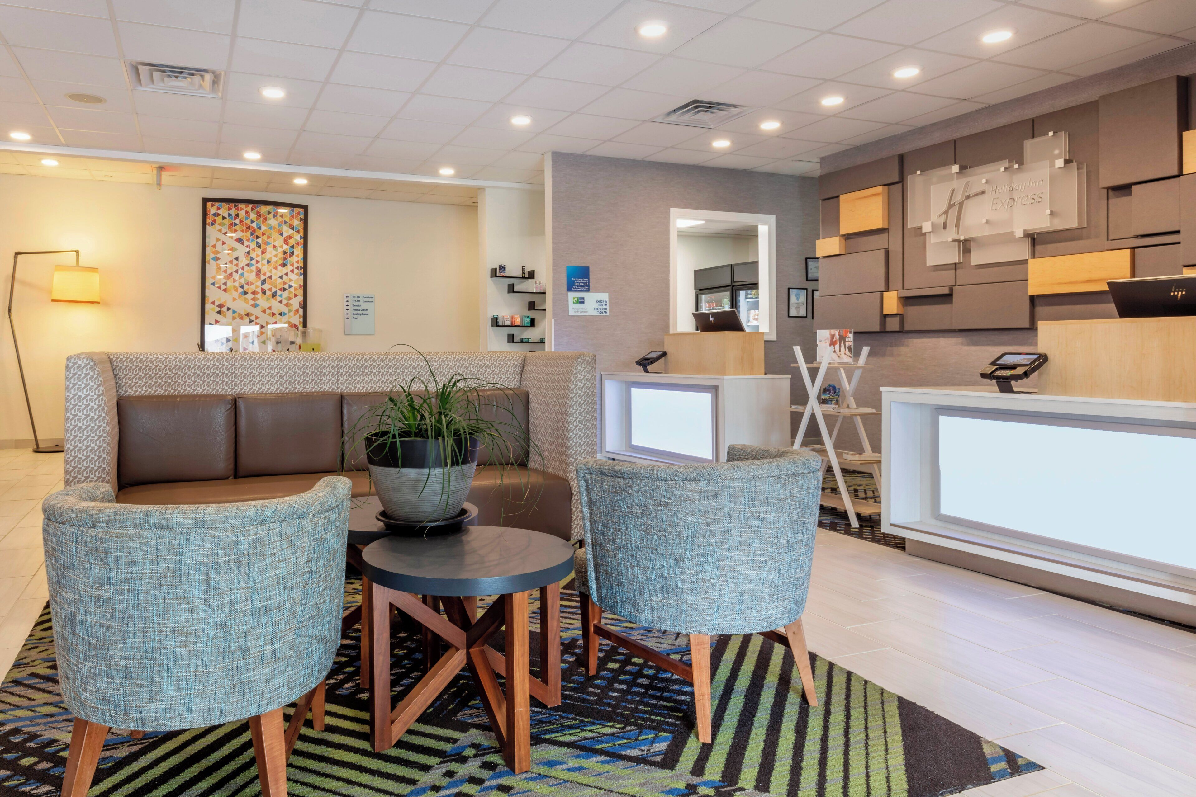A modern reception area with a seating arrangement, a reception desk, and a wall-mounted information board.