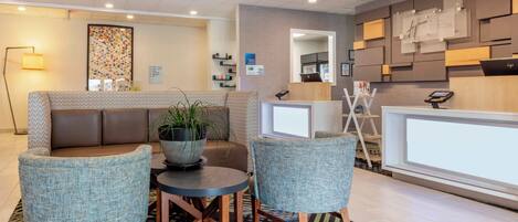A modern reception area with a seating arrangement, a reception desk, and a wall-mounted information board.