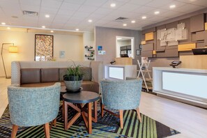 A modern reception area with a seating arrangement, a reception desk, and a wall-mounted information board.