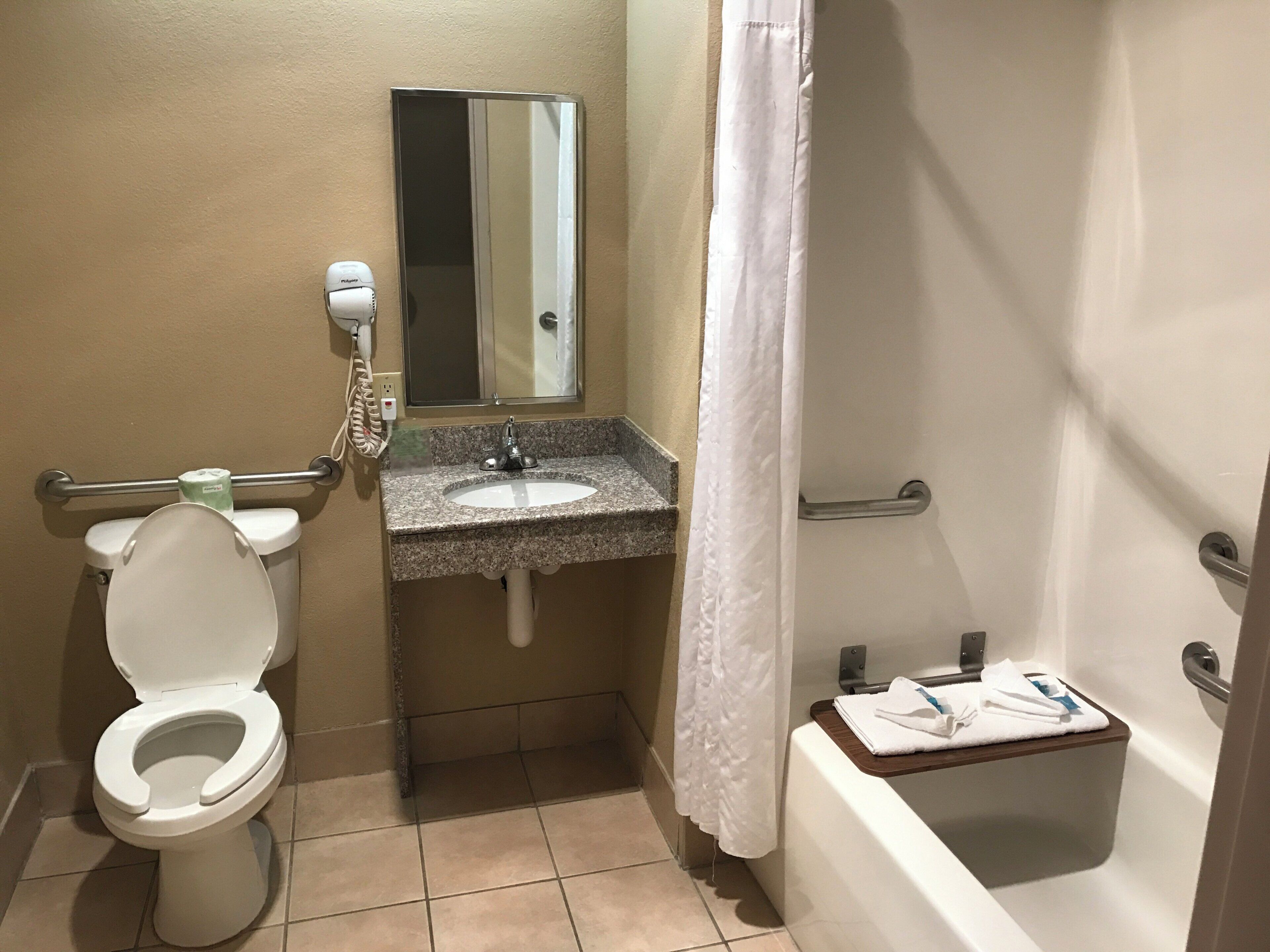 A bathroom with a toilet, sink, mirror, and bathtub.