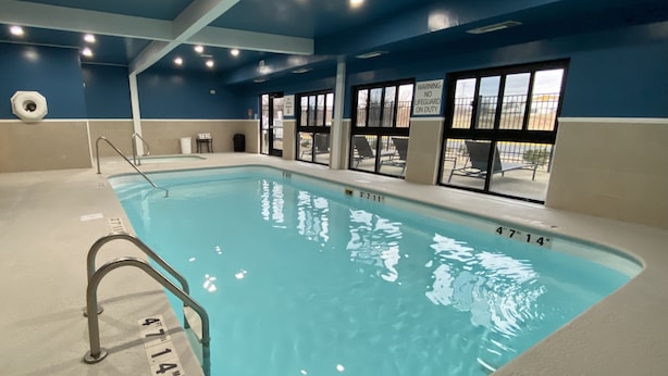 An indoor swimming pool with clear water, marked depth lines, and a lifeguard sign.