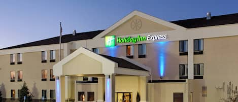 A Holiday Inn Express hotel with a covered entrance, a flagpole, and a parking lot.