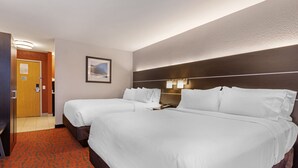 A hotel room with two beds, a wooden headboard, a framed picture on the wall, and a red carpet.