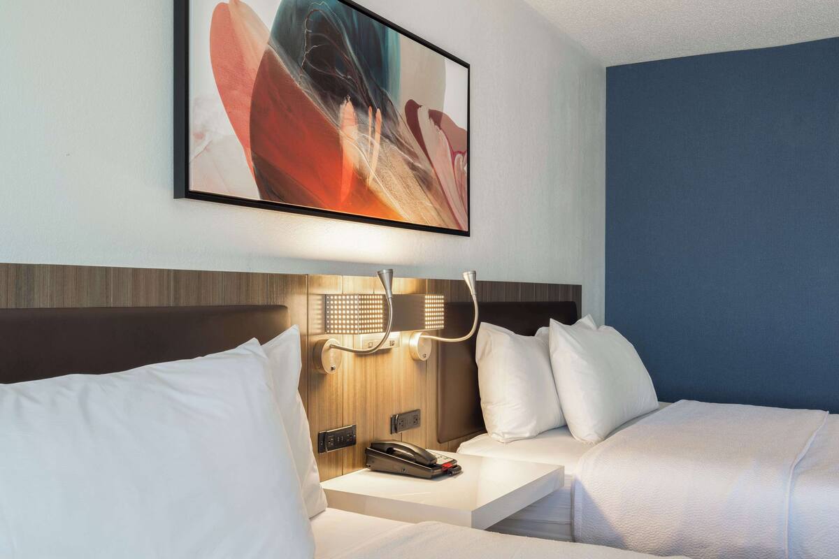 A hotel room with a bed, bedside table, and a wall-mounted artwork.