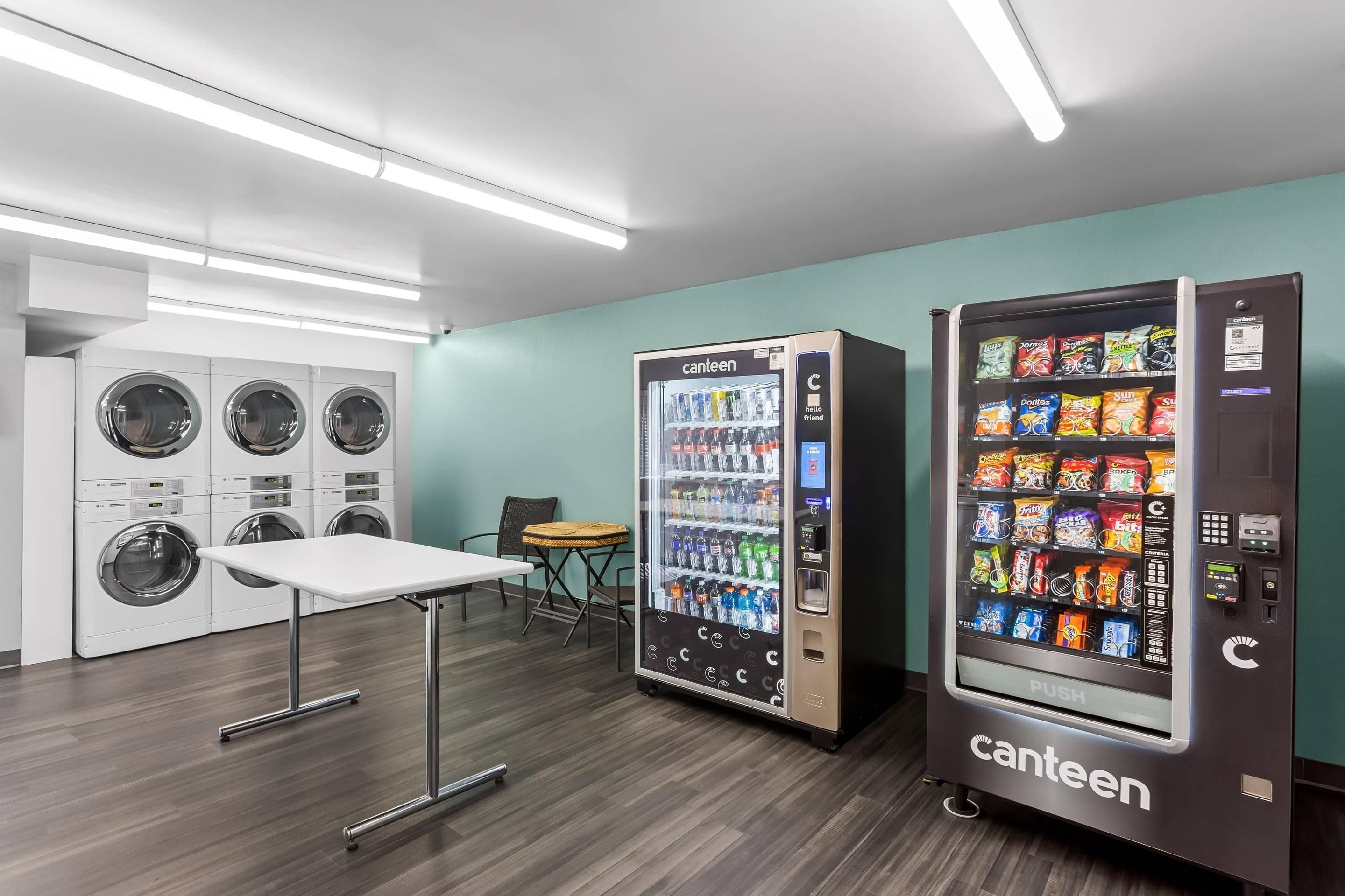 Una lavanderia self-service con tavoli, sedie e distributori automatici.
