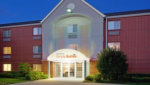 Ein Hotel mit Backsteinfassade, einem großen Eingang mit der Aufschrift "SONESTA Simply Suites" und einem gepflegten Rasenbereich.