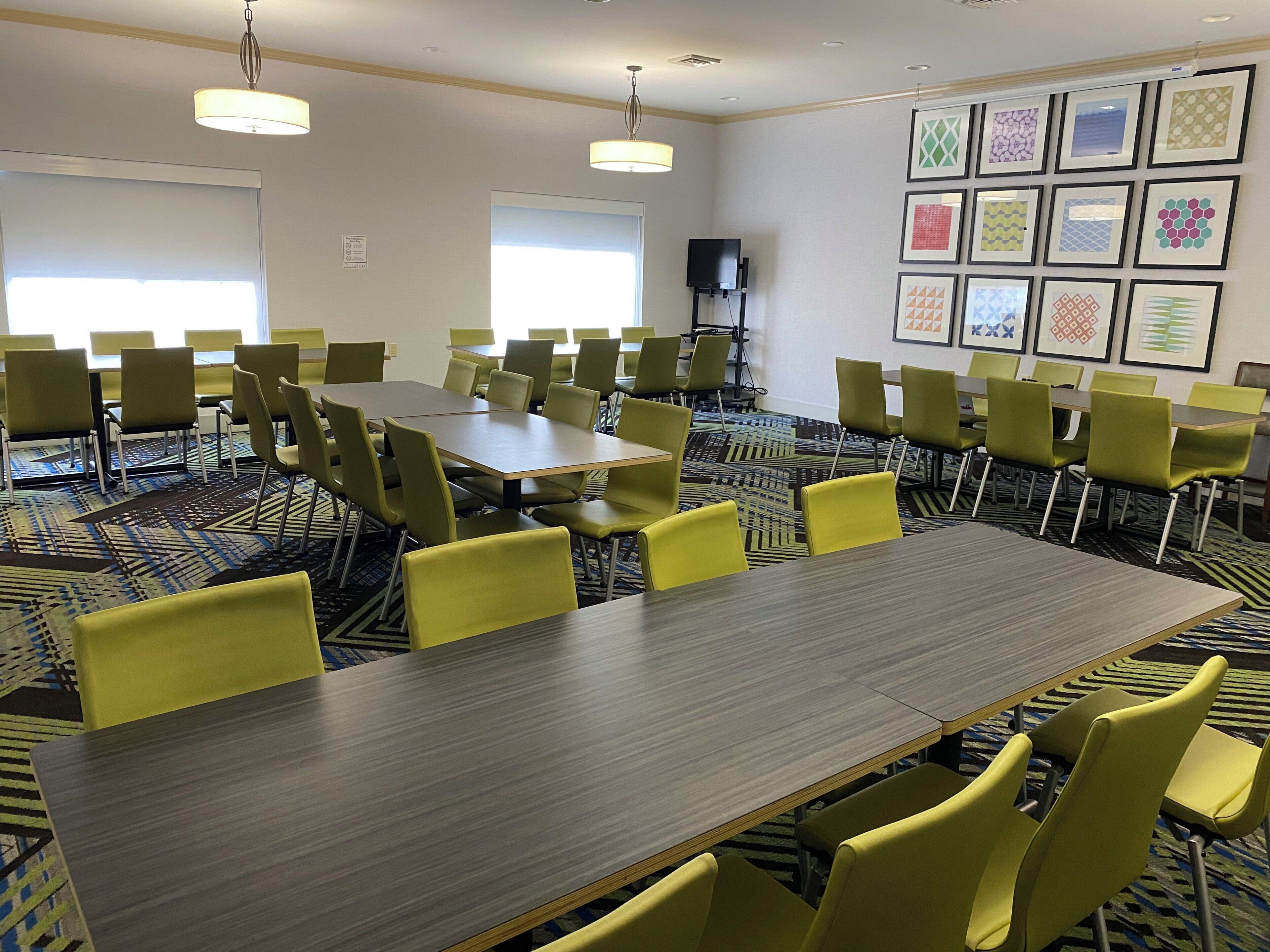 Una sala conferenze con un lungo tavolo, diverse sedie e quadri appesi alle pareti.