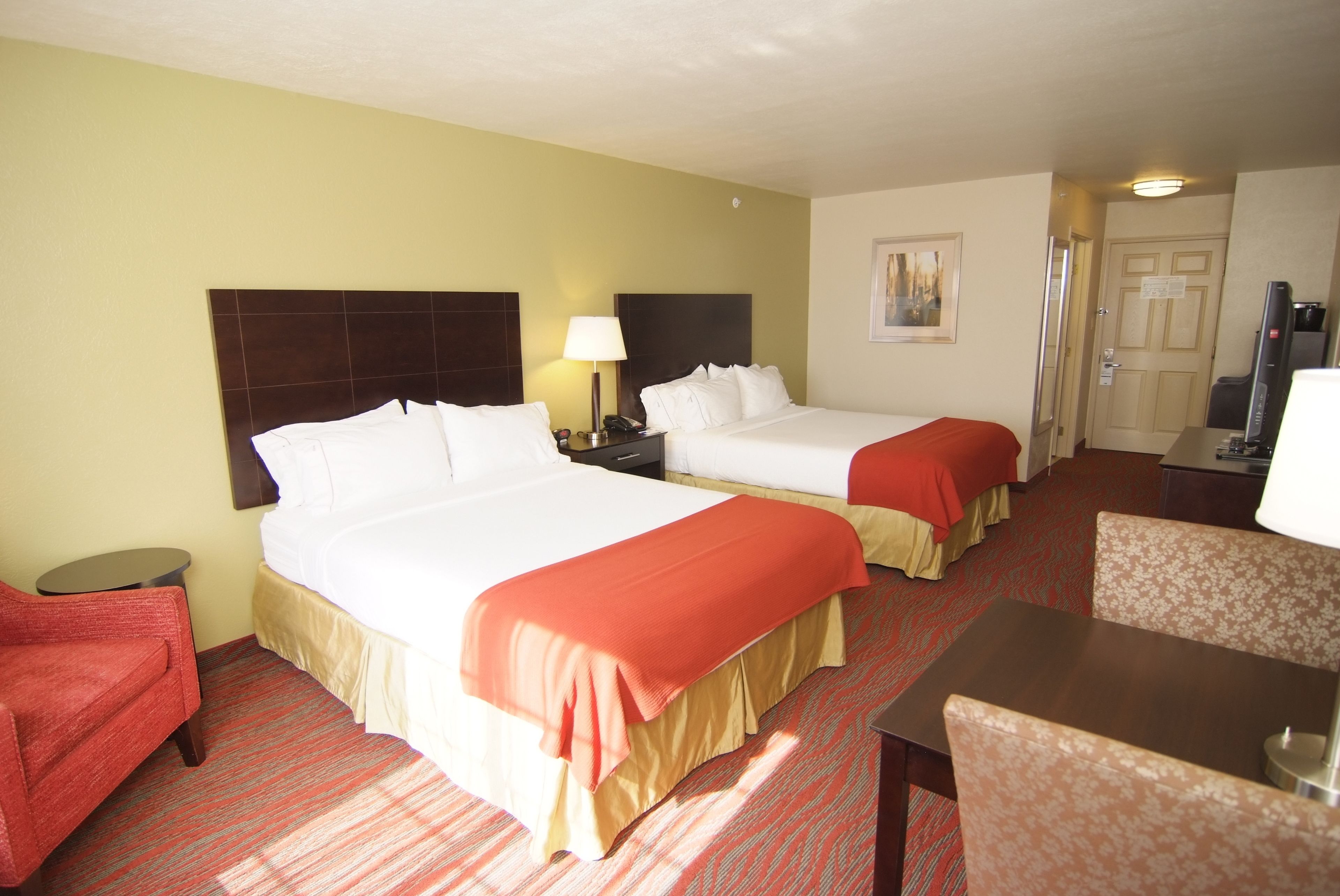 Une chambre d’hôtel avec deux lits, une petite table, une chaise et un téléviseur.