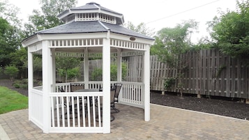 A white gazebo with a tiled roof and a brick patio.