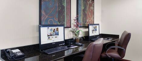 Habitación de hotel con escritorio, dos computadoras, teléfono y dos sillas.