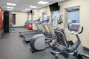A gym with treadmills, ellipticals, and a red exercise ball.
