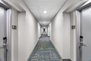 A hotel hallway with carpeted floors, white walls, and doors on both sides. - Hampton Inn Portage (Portage)