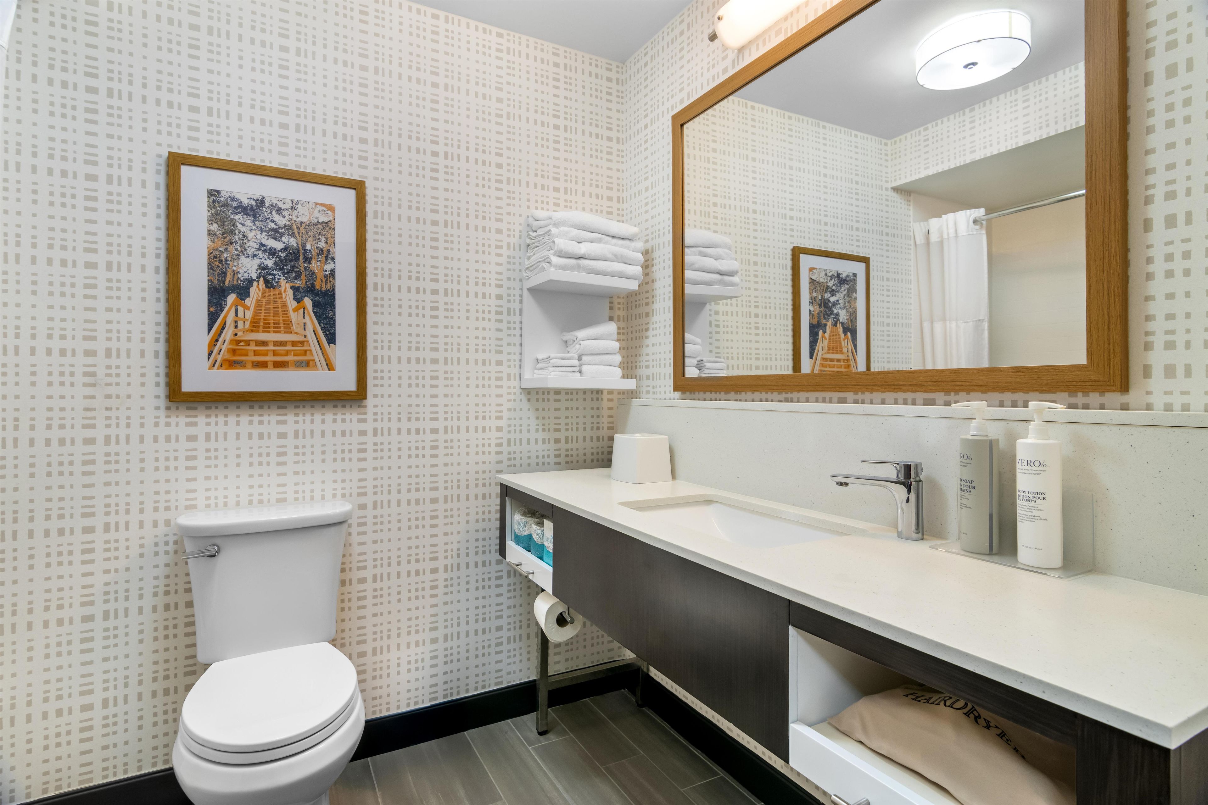 Uma casa de banho moderna com sanita, lavatório e espelho.