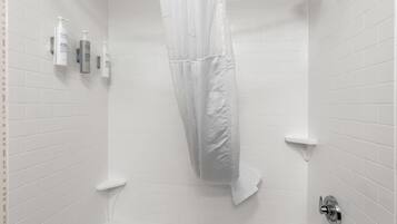 Ein Badezimmer mit weißen Fliesen, einer Duschvorhang und einer Badewanne.