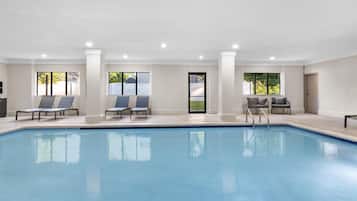 A swimming pool with lounge chairs and a door leading to a covered area.